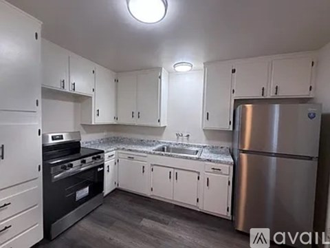 A kitchen with white cabinets and a stainless steel refrigerator.