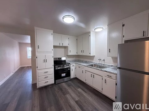 A kitchen with white cabinets and a stainless steel refrigerator.