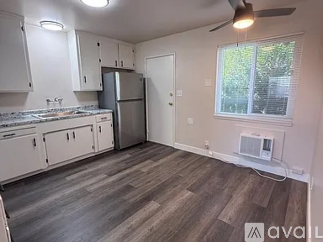 A kitchen with white cabinets and a wooden floor.
