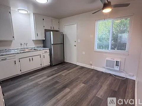 A kitchen with white cabinets and a wooden floor.