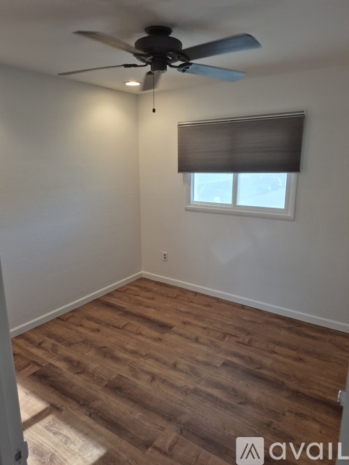A room with a ceiling fan and wooden flooring.