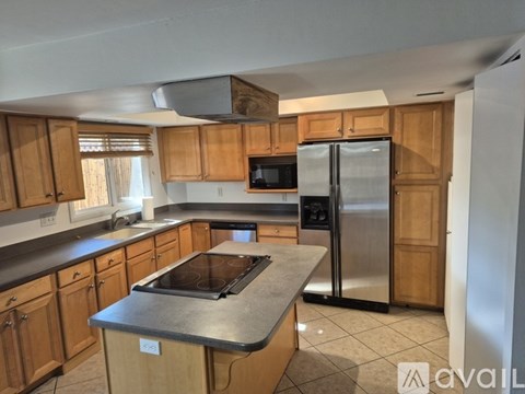 A kitchen with wooden cabinets and a stainless steel refrigerator.