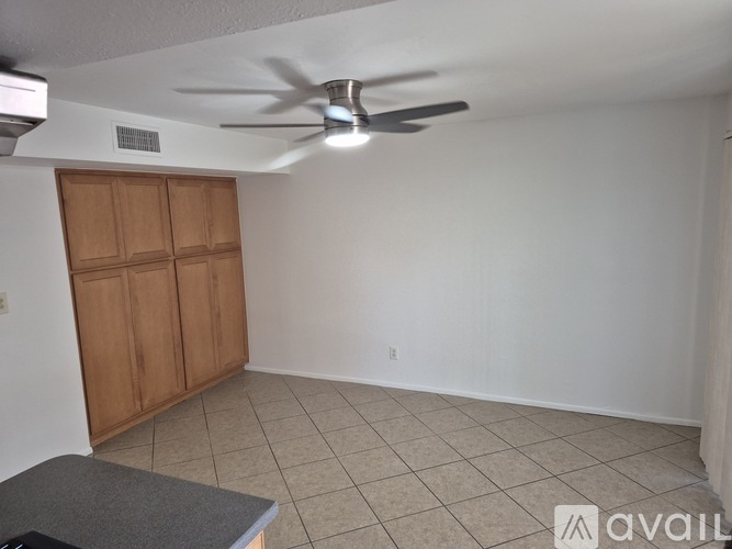 A room with a ceiling fan and a wooden cabinet.