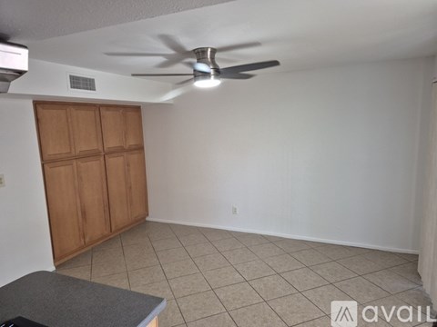 A room with a ceiling fan and a wooden cabinet.