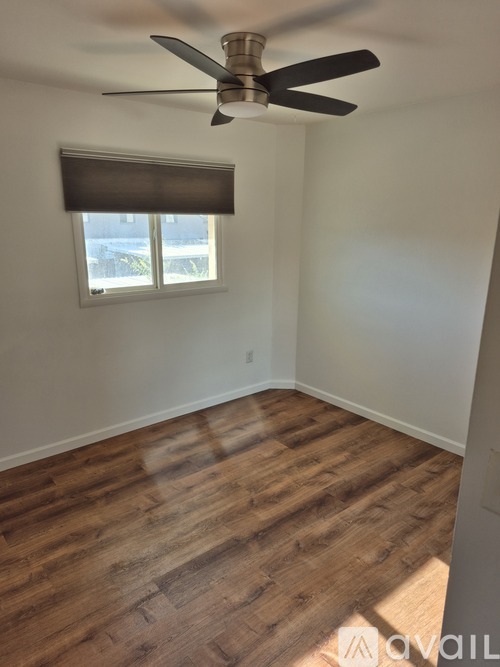 A room with a ceiling fan and wooden flooring.