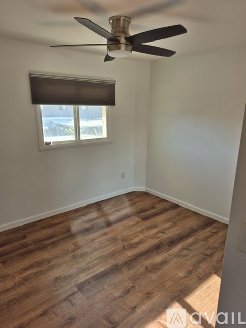 A room with a ceiling fan and wooden flooring.