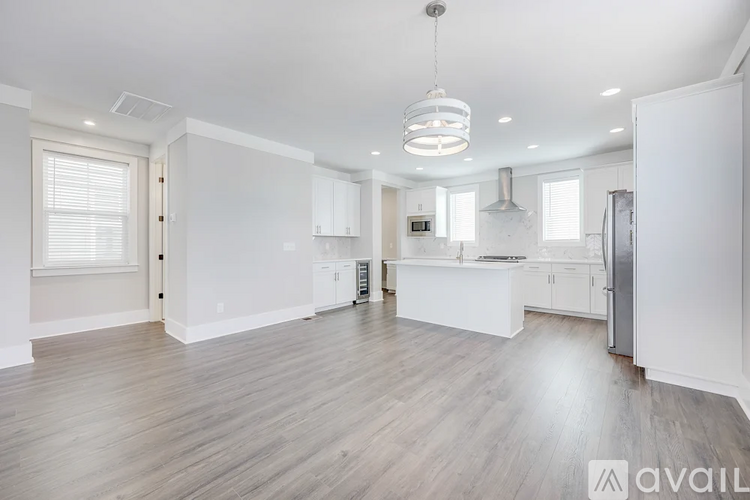 A spacious kitchen with white cabinets and a wooden floor.