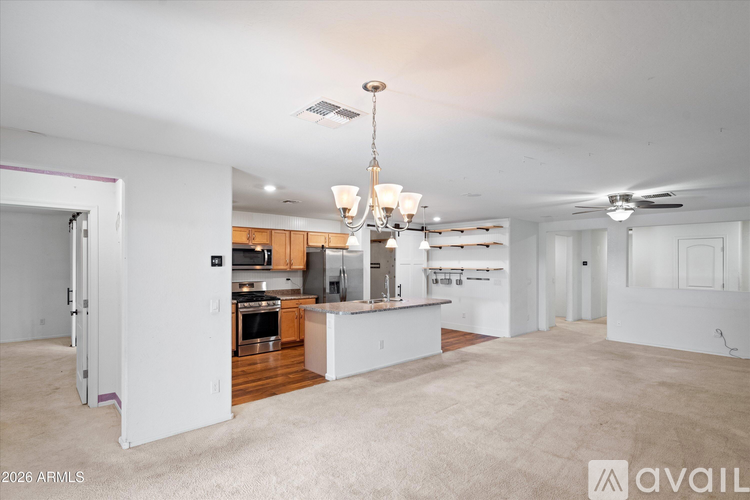 A spacious, empty living room with a kitchen in the background.