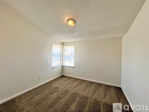 A spacious, empty living room with a kitchen in the background.