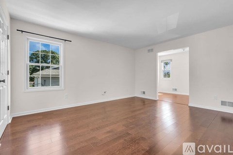 A spacious room with wooden floors and a large window.