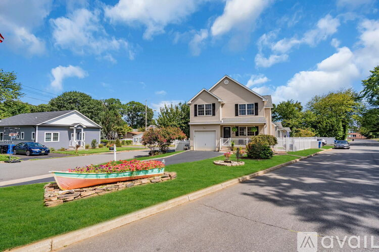 A house with a boat-shaped flower bed in front of it.