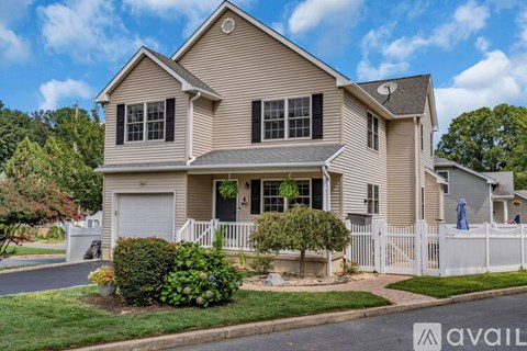 A house with a beige exterior and a white fence is for sale.