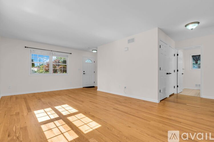A room with wooden floors and white walls, with a window that lets in natural light.