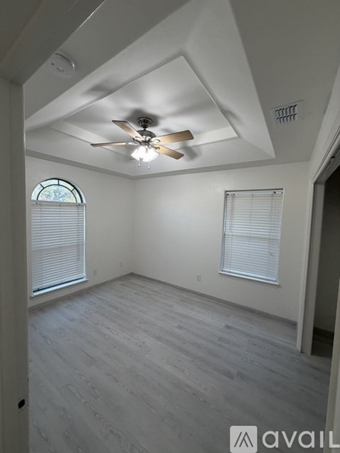 A room with a ceiling fan and two windows.