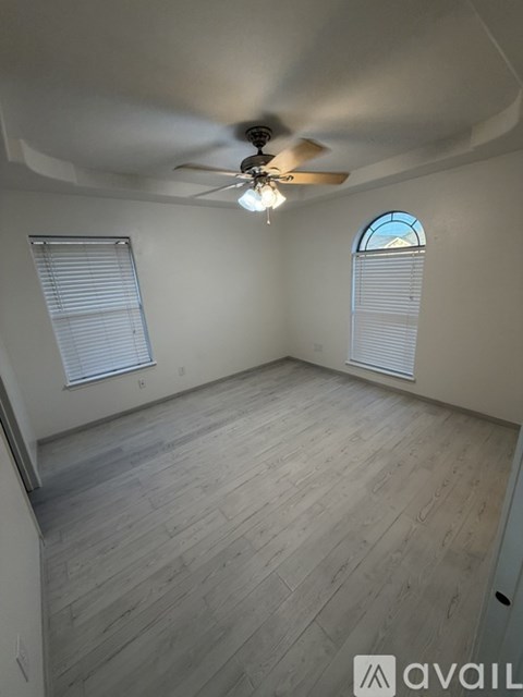 A room with a ceiling fan and two windows.