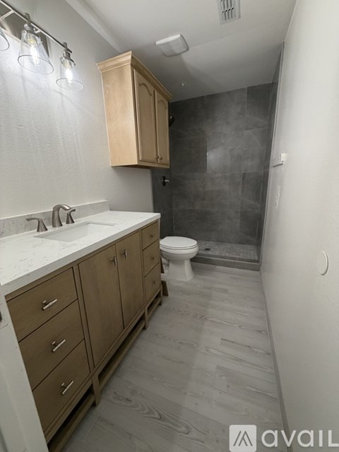 A bathroom with a toilet, sink, and wooden cabinets.