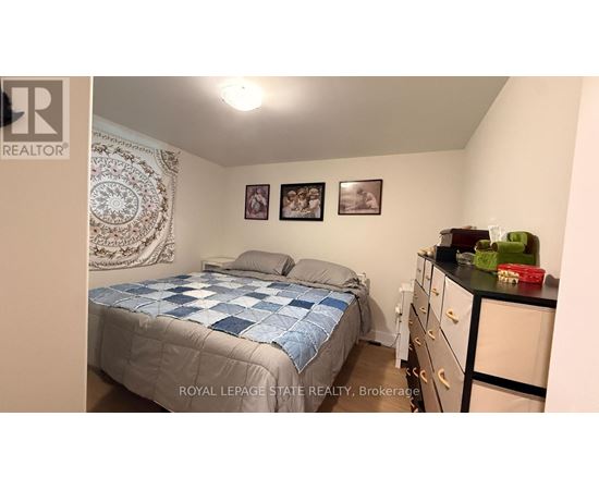 A bedroom with a bed, dresser, and two pictures on the wall.