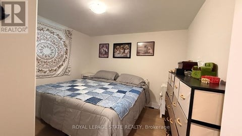 A bedroom with a bed, dresser, and two pictures on the wall.