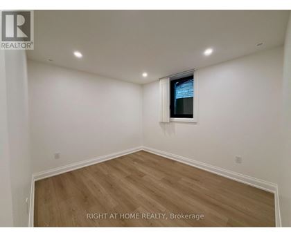 A room with wooden flooring and white walls, with a window on the wall.