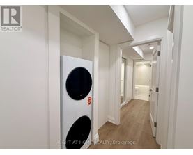A white washing machine is in a narrow hallway.