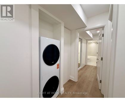 A white washing machine is in a narrow hallway.