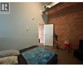 A bedroom with a brick wall and a bed with a blue comforter.