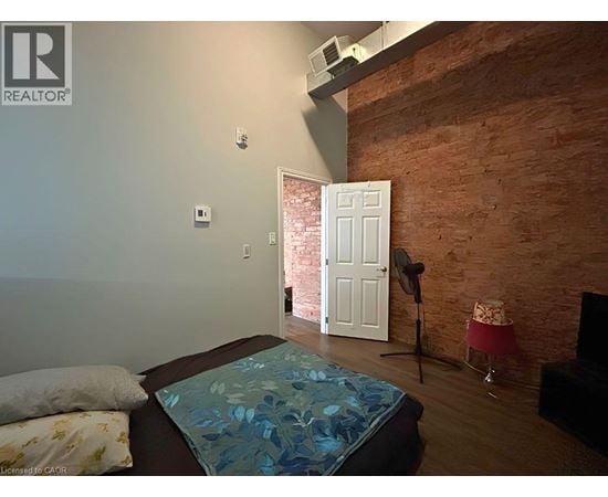 A bedroom with a brick wall and a bed with a blue comforter.