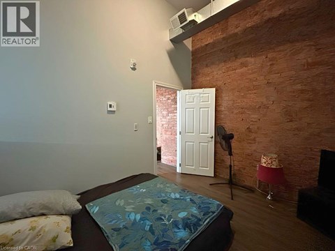 A bedroom with a brick wall and a bed with a blue comforter.