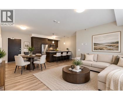 A well-lit, modern living room with a dining area and a kitchen in the background.