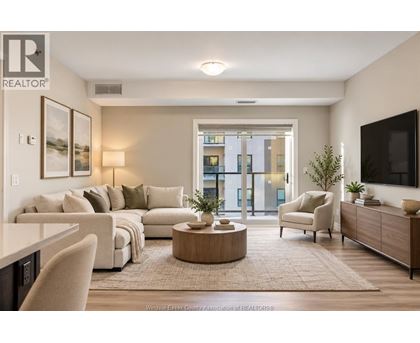 A well-lit living room with a large window, a sofa set, a coffee table, and a television.