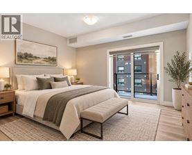 A bedroom with a large bed and a view of a building outside the window.