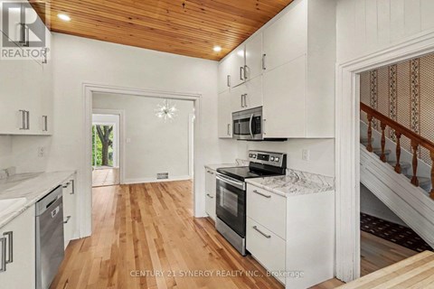 A kitchen with white cabinets and a wooden ceiling.