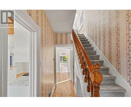 A hallway with a staircase and a doorway leading to a bedroom.