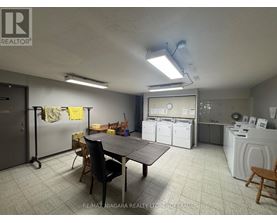 A laundry room with a washer and dryer, a table, chairs, and a refrigerator.
