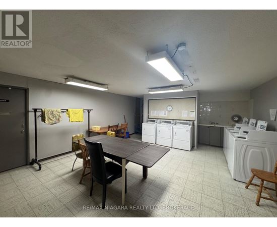 A laundry room with a washer and dryer, a table, chairs, and a refrigerator.