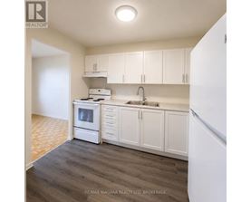A kitchen with white cabinets and a white refrigerator.