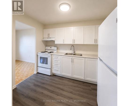 A kitchen with white cabinets and a white refrigerator.