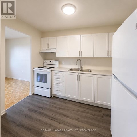 A kitchen with white cabinets and a white refrigerator.