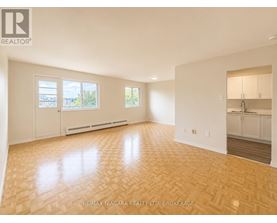 A spacious room with wooden flooring and white walls.