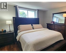 A bedroom with a large bed, a nightstand with a lamp, and a window with a view of trees.