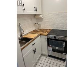 A kitchen with white cabinets and a black stove top oven.