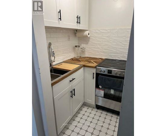 A kitchen with white cabinets and a black and white floor.