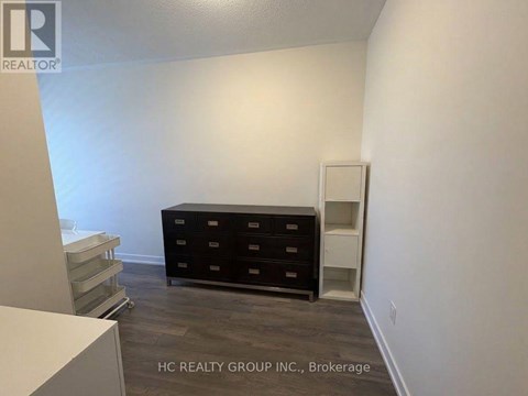 A room with a black dresser and a white cabinet.