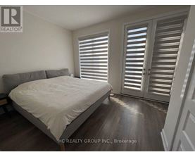 A bedroom with a bed, pillows, and a window with shutters.