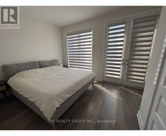 A bedroom with a bed, pillows, and a window with shutters.