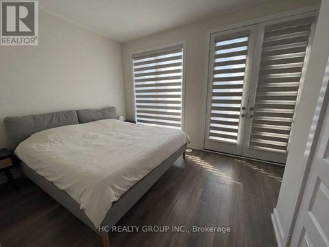 A bedroom with a bed, pillows, and a window with shutters.