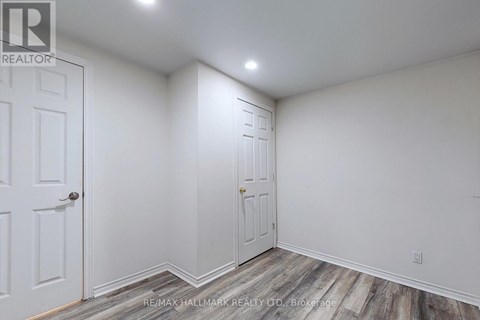 A white room with two doors and a wooden floor.