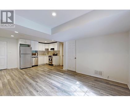 A spacious kitchen with white cabinets and a refrigerator.