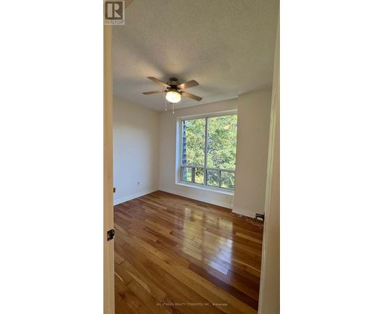 A room with a ceiling fan and wooden floors.