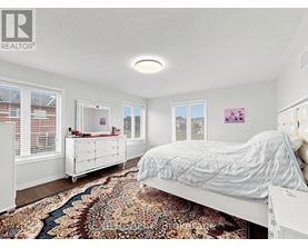 A bedroom with a large bed and a rug on the floor.